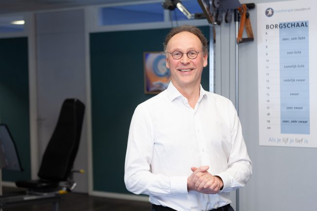 fysiotherapeut staat in zijn praktijk