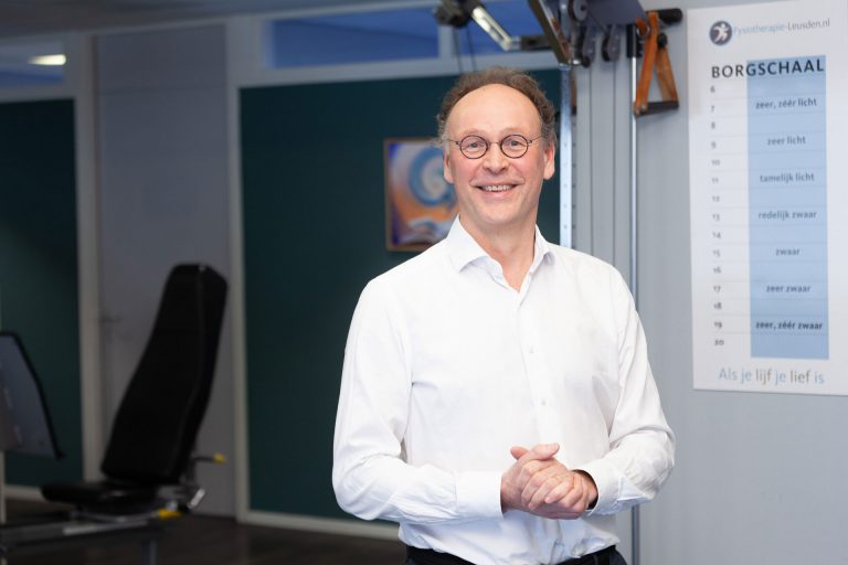 fysiotherapeut staat in zijn praktijk